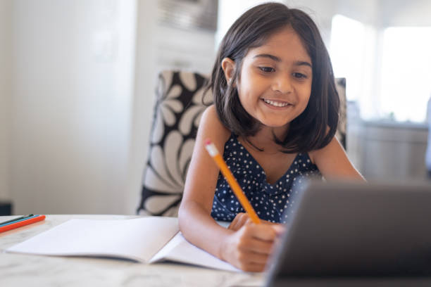 leuk basisleeftijdsmeisje dat laptopcomputer gebruikt terwijl het bijwonen van school online - huiswerk stockfoto's en -beelden