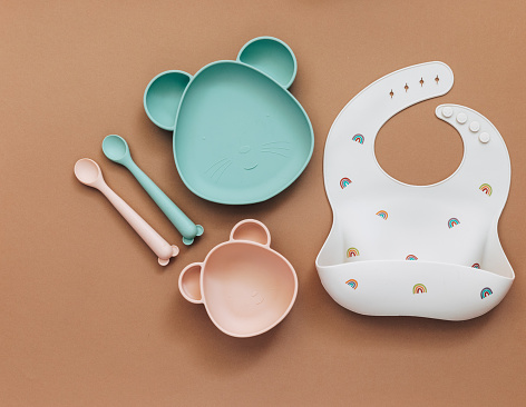 Cute Flat lay composition with baby accessories and tableware for food on light background. First food for kids concept