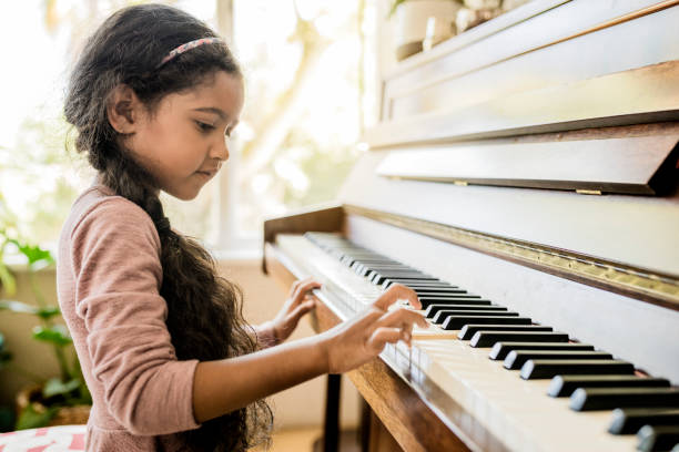 Cute girl playing piano at home stock photo