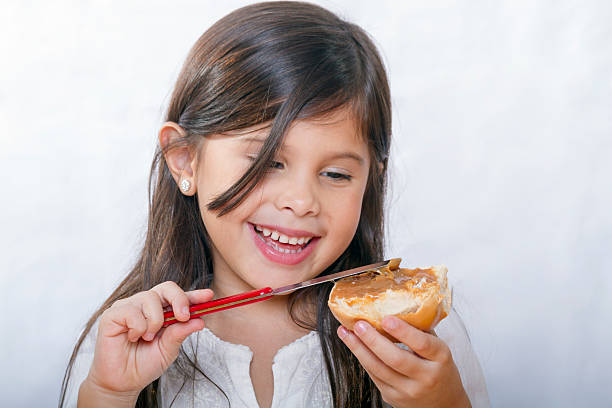 cute latina girl with long hair smiles as bread smeared stock photo
