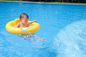 かわいい小さなアジア 2 歳幼児男の子子供屋外で浮き輪で遊んで楽しんで暑い夏の日のプール