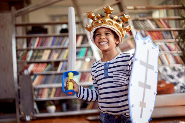 A cute little boy dressed as knight is posing for a photo while playing at home. Family, home, playtime stock photo