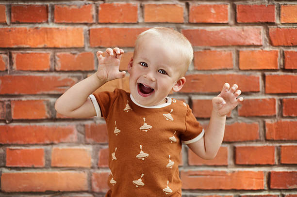 Cute little boy Cute little boy making funny faces on a brick wall background charades stock pictures, royalty-free photos & images