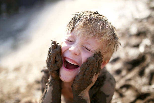 Cute Little Boy Playing Outside in the Mud with a Dirty Face stock photo
