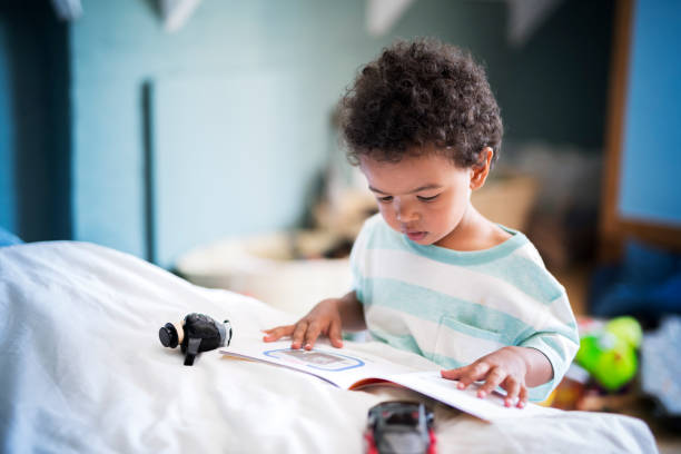 Cute little boy reading book at home stock photo
