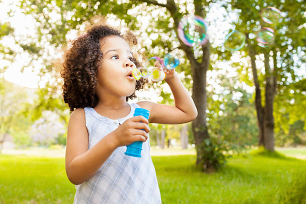 Cute Little Girl Blowing Bubbles Beautiful little girl blowing bubbles in park. Horizontal Shot. Please checkout our lightboxes  bubble wand stock pictures, royalty-free photos & images