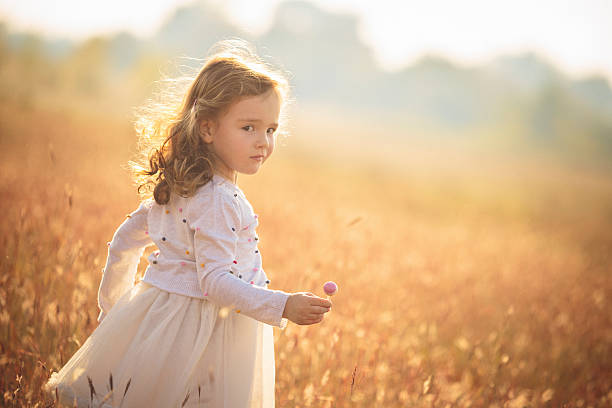 Cute little girl holding lollipop outdoors in nature stock photo