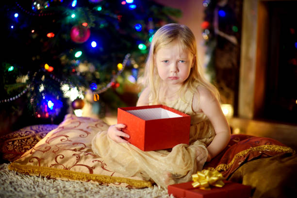 Cute little girl is unhappy with her Christmas gift stock photo