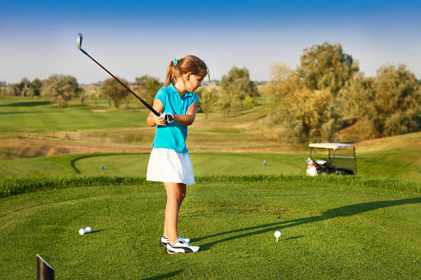 Cute little girl playing golf on a field outdoor stock photo