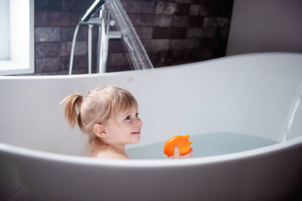 Cute little girl playing in a bathtub Cute little girl of 2-3 years old playing in a bathtub. Photo was taken in Quebec Canada bathtub stock pictures, royalty-free photos & images