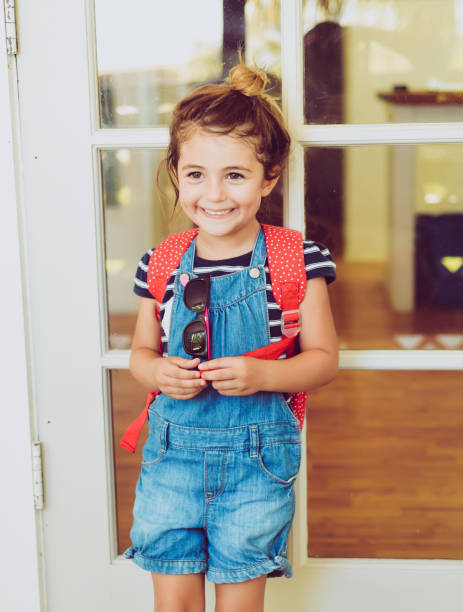 Cute little girl wearing backpack headed to her very first day of school stock photo