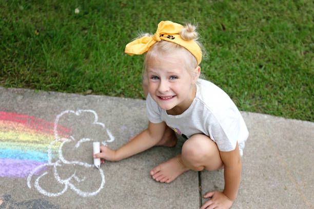 Cute Little Kid Coloring with Sidewalk Chalk Outside stock photo
