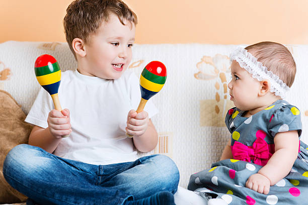 Cute little sister and her brother sitting with maracas stock photo