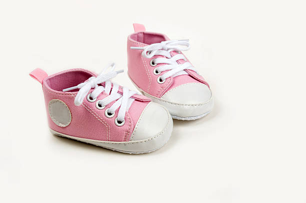 Cute pink baby girl sneakers close up on gray background stock photo