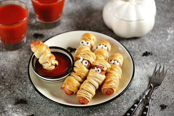 Cute sausages in the dough "Mummy" with ketchup and spiders for the Halloween party. Children's food. stock photo