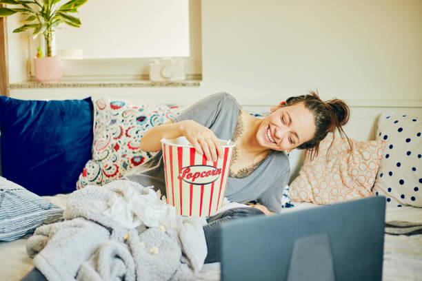 Cute woman eat popcorn and watching movie at home. stock photo