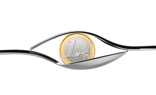 Eye shaped cutlery with one Euro coin isolated on white background.