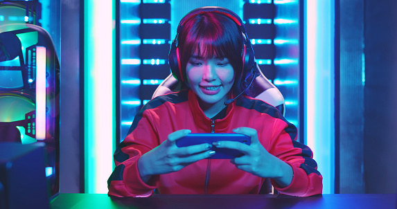 Young Asian Pretty Pro Gamer win in Online Video Game and cheer with hand up