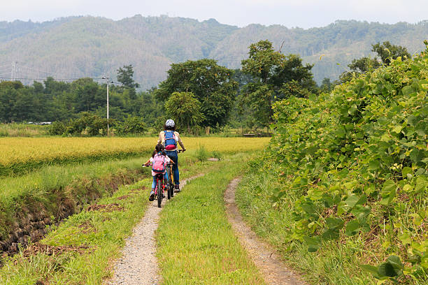 cycling in the country Two people make cycling in a Japanese rural scenery. satoyama scenery stock pictures, royalty-free photos & images