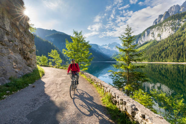 Cycling senior at Gosausee with dachstein view - European Alps Cycling senior at Gosausee with dachstein view - European Alps, Austria dachstein mountains stock pictures, royalty-free photos & images