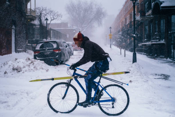 Cycling with ski equipement during the snowstorm stock photo