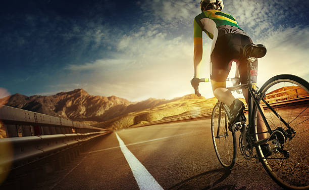 Cyclist riding a bike to the sunset on the highway stock photo