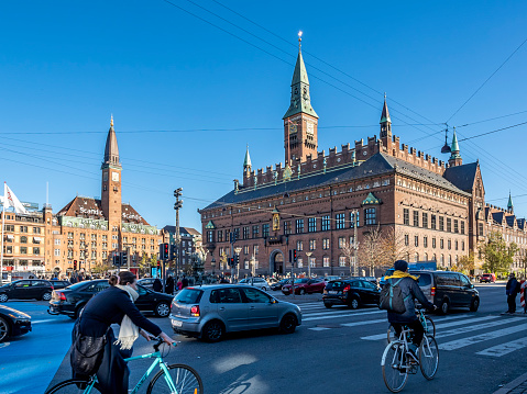 Copenhagen, Denmark - Oct 18, 2018: Cyclists and motorists on the zebra crossing that leads to the historic Copenhagen City Hall (1905) Council Building along the Hans Christian Andersens Boulevard.