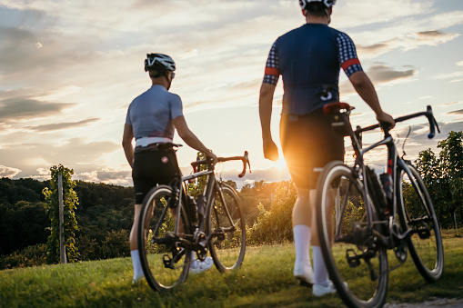 Cyclists making a stop by the vineyard at sunset.