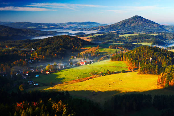 Czech typical autumn landscape. Hills and villages with foggy morning. Morning fall valley of Bohemian Switzerland park. Hills with fog, landscape of Czech Republic, Jetrichovice, Ceske Svycarsko. stock photo