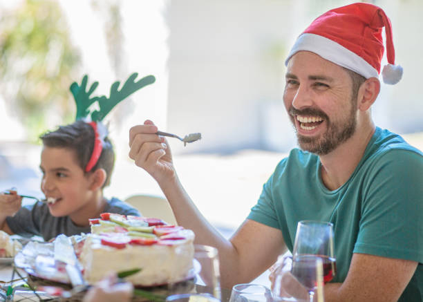 Dad smiling and laughing at table over Christmas lunch Australian Christmas family celebrations and eating with children pavlova dessert photos stock pictures, royalty-free photos & images