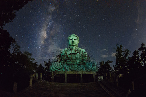 Daibutsu or 'Giant Buddha' is a Japanese term often used informally for a large statue of Buddha, Time lapse Giant Buddha with milky way moving in sky at night, Mae Tha District, Lampang Province.