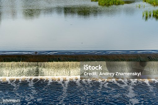 istock dam on a small river. Water flows from a small river dam, boils, foams 1414998411