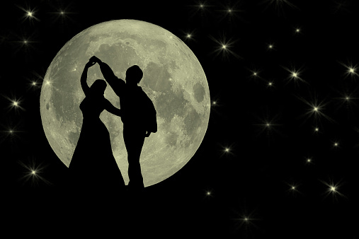 Silhouette of two people dancing in the moonlight