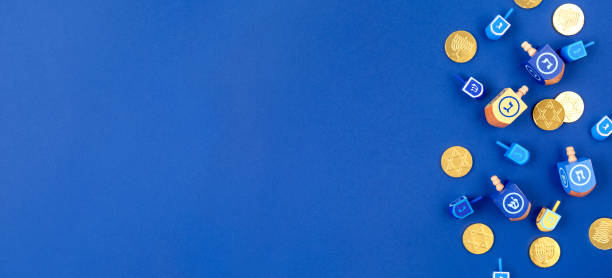 fondo azul oscuro con dreidels multicolores y monedas de chocolate. concepto de vacaciones hanukkah y judaico. - hanukkah fotografías e imágenes de stock