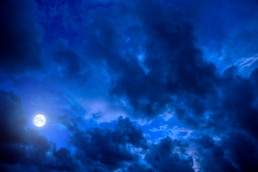 Empty dramatic dark blue night sky with full moon and storm clouds