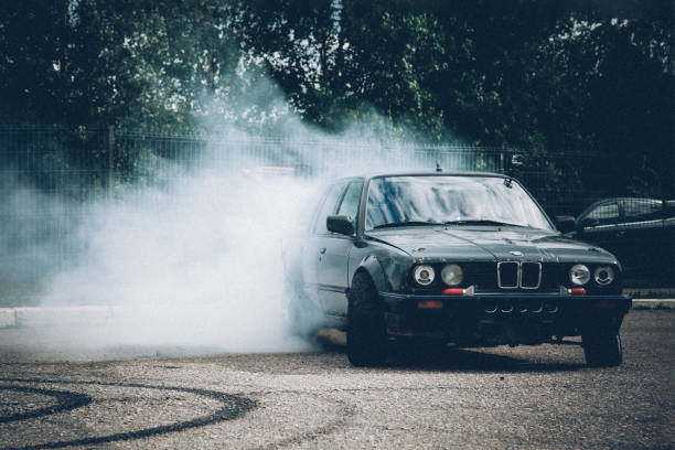 A dark BMW car drifts in the parking lot. A lot of smoke, a burnout. Illegal drift. Law violation. stock photo