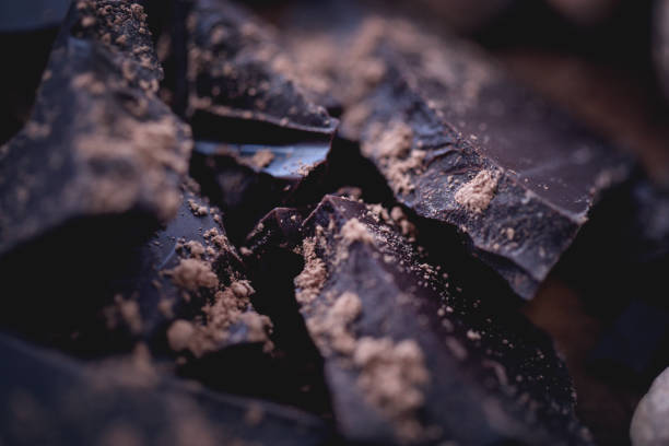 Dark chocolate bar crushed and sprinkled with cocoa powder with spices stock photo