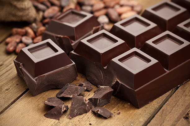 dark chocolate bar on rustic wood table - chocolade stockfoto's en -beelden