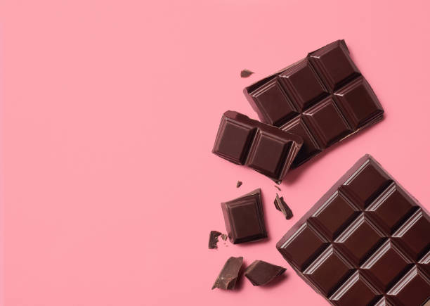 donkere chocolade op roze achtergrond - chocolade stockfoto's en -beelden
