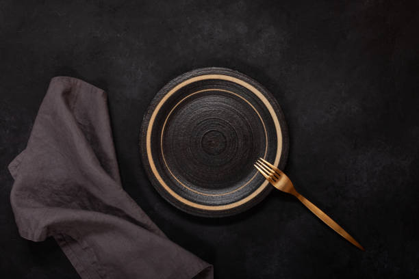 Dark dishes on black background Empty ceramic plate and fork on black background linen photos stock pictures, royalty-free photos & images