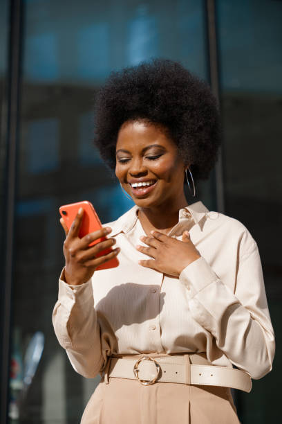 A dark skinned surprised business woman just got good news for her business in a message on her smart phone stock photo