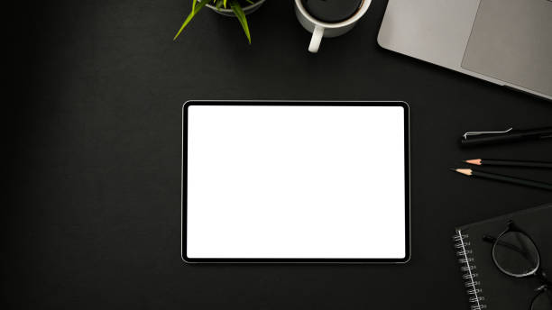 Dark workspace with wireless tablet mockup on black background. stock photo