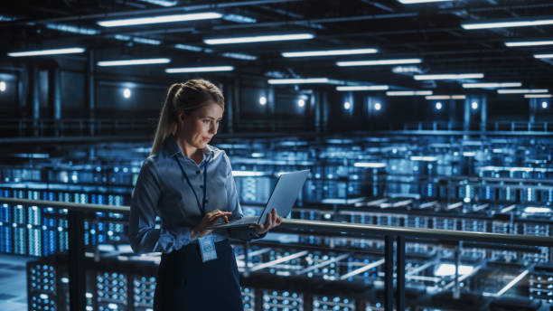 Data Center Female It Specialist Using Laptop. Server Farm Cloud Computing and Cyber Security Maintenance Administrator Working on Computer. Information Technology Professional. stock photo