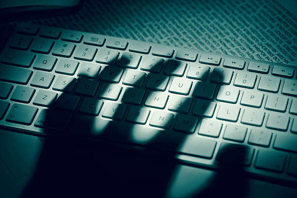 Data thief’s hand shadow on computer keyboard stock photo