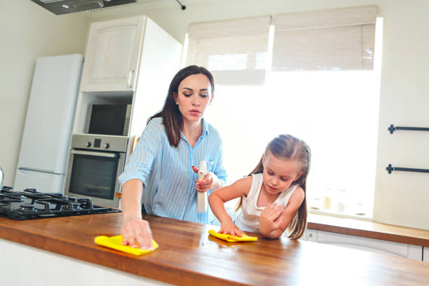Daughter and mother cleaning kitchen table stock photo