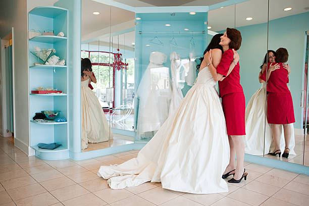 Daughter trying on wedding dress, embracing mother  mother of the bride dress stock pictures, royalty-free photos & images