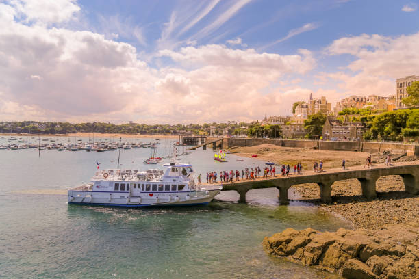 Day tripping tourists line up to start boarding ferry on the return trip to Saint Malo from Dinard pier. stock photo