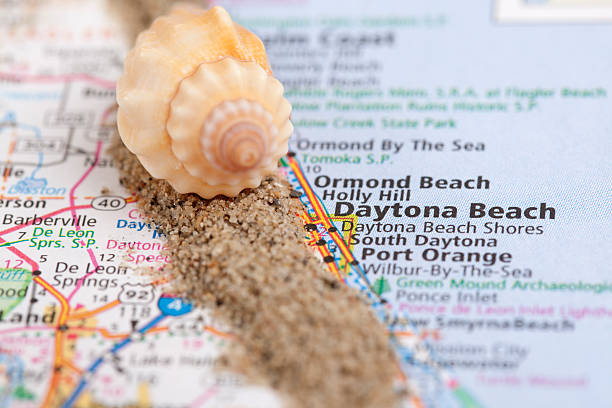 Daytona Beach, Florida on a Road Map Daytona Beach on a road map. Shallow depth of field. Sand and sea shells represent the beach. florida beaches map stock pictures, royalty-free photos & images