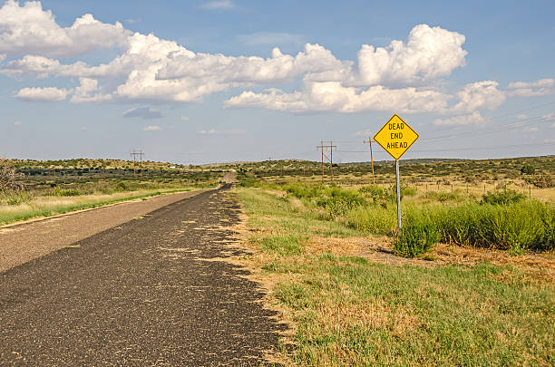 Dead End Ahead Sign Rural area along Route 66 with a sign for a dead end ahead.  It looks like there is a gate across the road. dead end road stock pictures, royalty-free photos & images