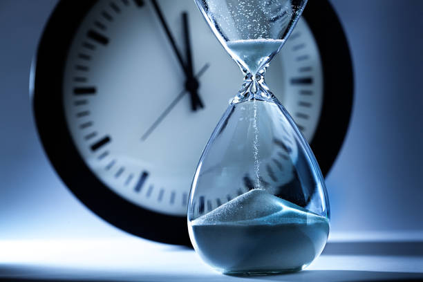 Deadline and Out of Time: Sand Timer Hourglass and Clock at Midnight stock photo